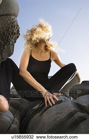 Low angle view of Caucasian mid-adult woman crouching on rocks with hair blowing wildly in wind. View Large Photo Image Stock Image - Low angle view of Caucasian mid-adult woman crouching on rocks with hair blowing wildly in wind.. Fotosearch