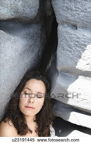 Stock Photography - Portrait of brunette Caucasian mid-adult woman by rock formation with eyes closed.. Fotosearch