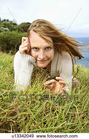 Portrait of young redheaded woman lying in grass looking at viewer with devilish grin. View Large Photo Image Stock Photo - Portrait of young redheaded woman lying in grass looking at viewer with devilish grin.. Fotosearch