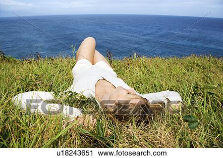 Portrait of young redheaded woman relaxing in grass above the ocean in Maui, Hawaii. View Large Photo Image Stock Image - Portrait of young redheaded woman relaxing in grass above the ocean in Maui, Hawaii. . Fotosearch