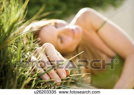 Stock Photography - Selective focus portrait of young woman relaxing in grass. Fotosearch