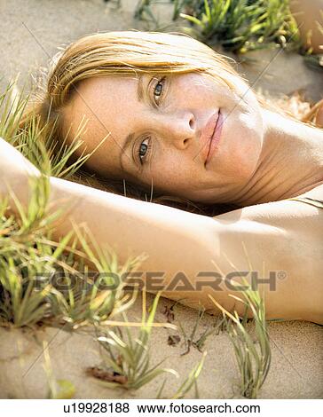 Stock Photo - Woman lying in grassy sand . Fotosearch