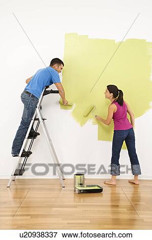 Attractive young adult couple painting interior wall of house. View Large Photo Image Stock Photo - Attractive young adult couple painting interior wall of house.. Fotosearch