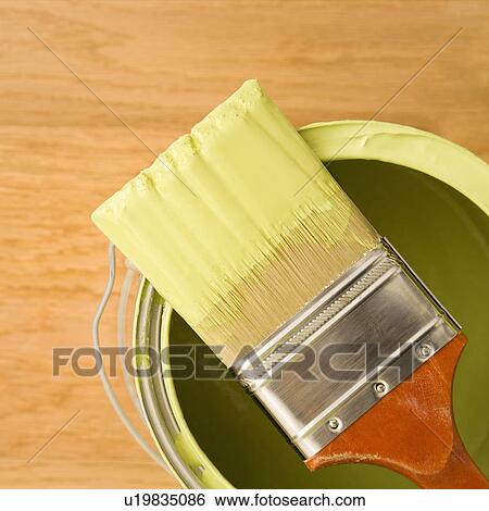 Stock Photograph - High angle view of paintbrush resting on paint can. Fotosearch