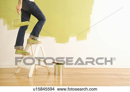 Legs of woman climbing stepladder holding paint roller. View Large Photo Image Picture - Legs of woman climbing stepladder holding paint roller.. Fotosearch