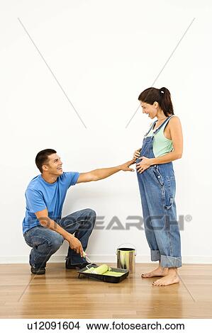 Pregnant woman and husband preparing to paint interior home wall View Large Photo Image Picture - Pregnant woman and husband preparing to paint interior home wall. Fotosearch