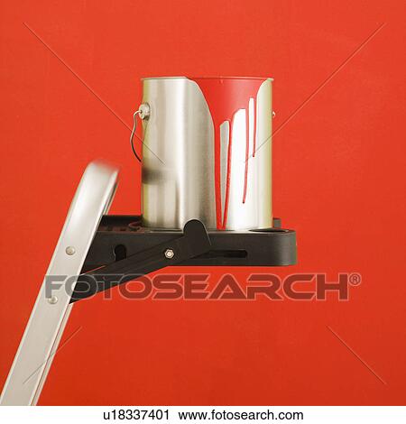Stock Image - Still life of paint can on step ladder in front of red wall.. Fotosearch