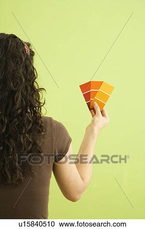 Stock Image - Woman holding paint color swatches. Fotosearch