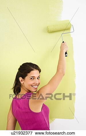 Stock Photo - Woman painting interior wall of home with paint roller. Fotosearch