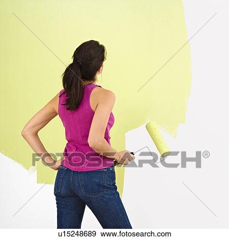 Woman standing and looking at partially painted wall holding paint roller View Large Photo Image Stock Photo - Woman standing and looking at partially painted wall holding paint roller. Fotosearch