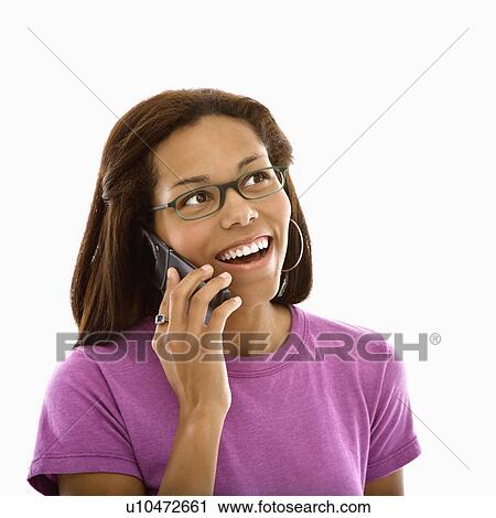 Stock Image - African American mid adult woman wearing glasses talking on cell phone and smiling.. Fotosearch