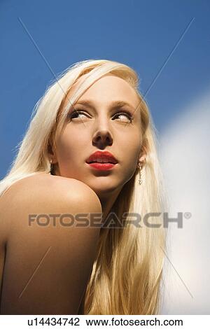 Stock Image - Portrait of attractive blonde Caucasian young adult woman looking over shoulder.. Fotosearch