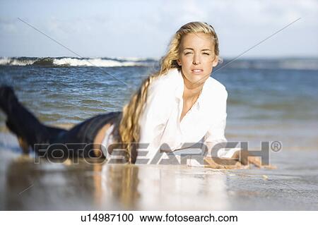 Stock Image - Portrait of pretty blond Caucasian woman lying on stomach on Maui, Hawaii beach.. Fotosearch