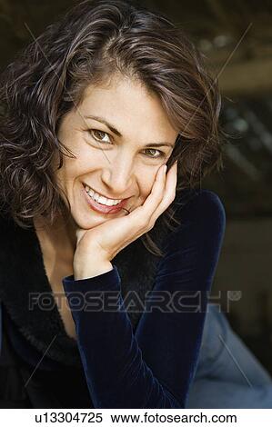 Portrait of pretty mid adult woman smiling with head on hand making eye contact View Large Photo Image Stock Photography - Portrait of pretty mid adult woman smiling with head on hand making eye contact. Fotosearch