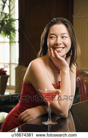 Taiwanese mid adult woman in red dress smiling and standing at bar with drink. View Large Photo Image Stock Image - Taiwanese mid adult woman in red dress smiling and standing at bar with drink.. Fotosearch