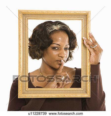 Stock Photo - Woman holding frame around head holding finger up to lips. Fotosearch