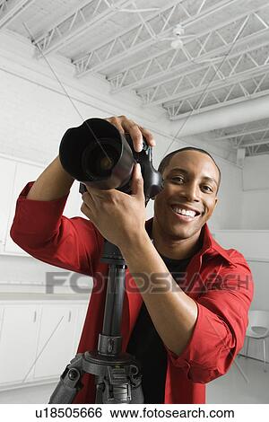 Stock Photograph - Adult with camera on tripod . Fotosearch