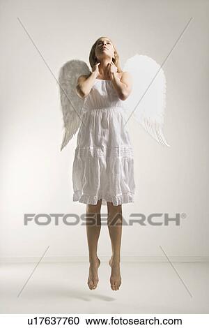 Stock Image - Angel in costume jumping in air. Fotosearch