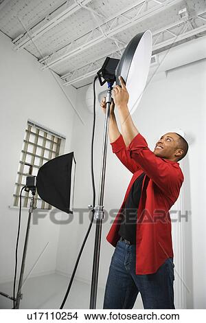 Picture - male adjusting studio lights. Fotosearch