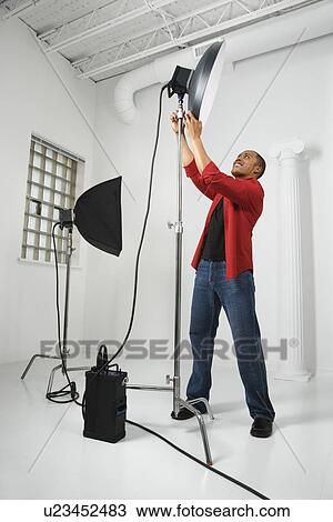 Stock Image - Male adjusting studio lights. Fotosearch