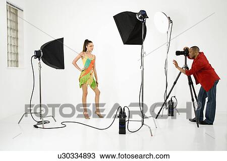 Stock Image - Model being photographed in studio by a male photographer. Fotosearch