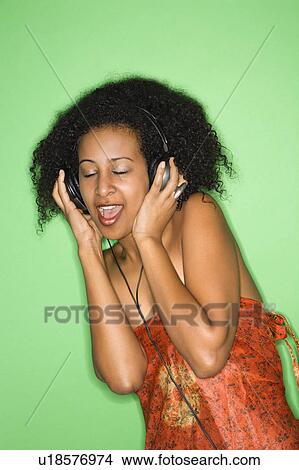 Picture - Woman listening to music through headphones. Fotosearch