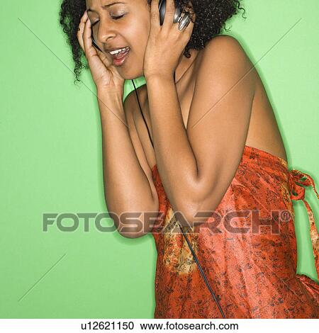 Stock Image - Woman listening to music through headphones. Fotosearch