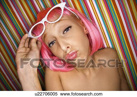 Stock Photography - Woman wearing pink wig against striped background making sassy expression. Fotosearch