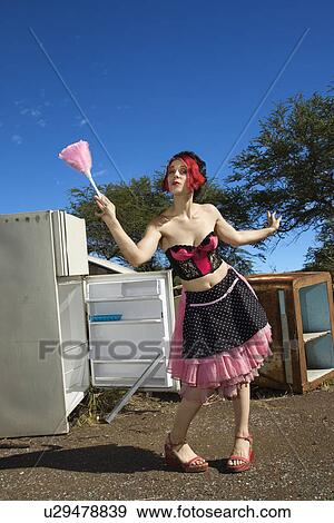 Stock Photo - Young adult Caucasian female house cleaning in junkyard.. Fotosearch
