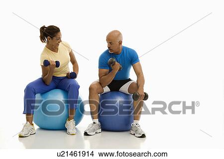 Picture - Balancing on exercise balls while working out with dumbbells. Fotosearch