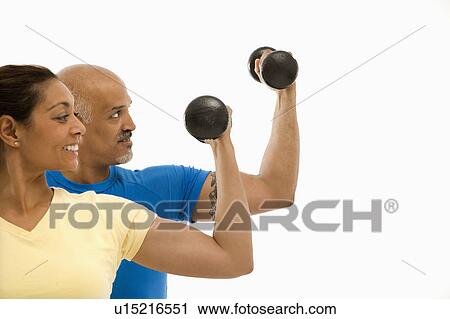 Stock Image - Exercising with dumbbells doing bicep curls. Fotosearch