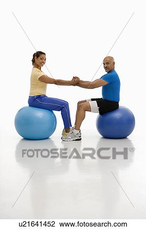 Stock Image - Man and woman balancing on exercise balls . Fotosearch