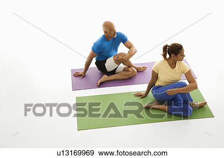 Stock Photo - Man and woman sitting stretching on exercise mats. Fotosearch