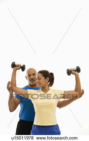 Man assisting woman with dumbbells View Large Photo Image Stock Photo - Man assisting woman with dumbbells. Fotosearch