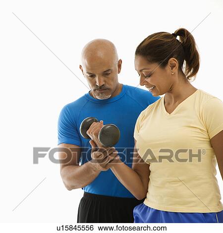 Man assisting woman with dumbbells View Large Photo Image Stock Photograph - Man assisting woman with dumbbells. Fotosearch