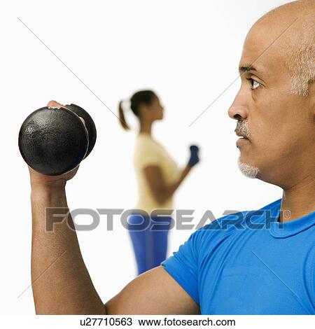 Man exercising using dumbbells with woman in background View Large Photo Image Stock Image - Man exercising using dumbbells with woman in background. Fotosearch