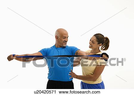 Woman assisting man with stretching band View Large Photo Image Stock Image - Woman assisting man with stretching band. Fotosearch