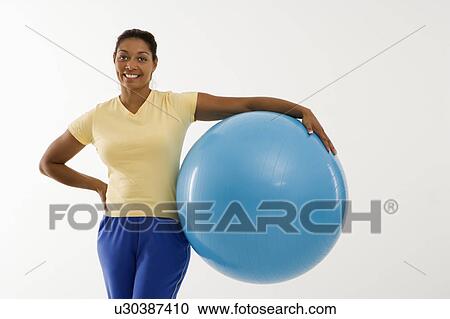 Woman standing and holding exercise ball View Large Photo Image Stock Image - Woman standing and holding exercise ball. Fotosearch