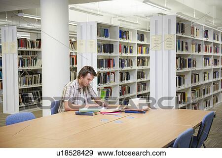 Stock Photo - Young man working in library. Fotosearch