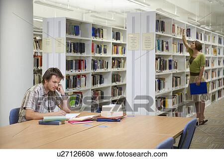 Young man working in library View Large Photo Image Stock Photo - Young man working in library. Fotosearch