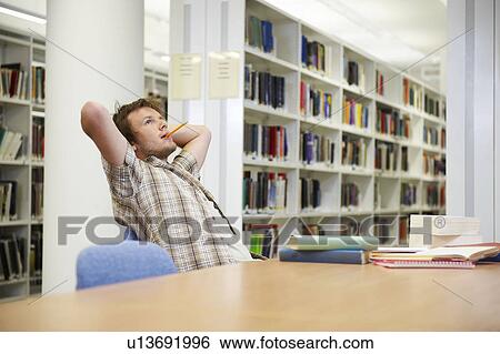 Stock Photograph - Young man working in library. Fotosearch