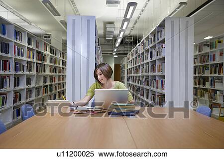 Stock Photography - Young multitasking student in library. Fotosearch