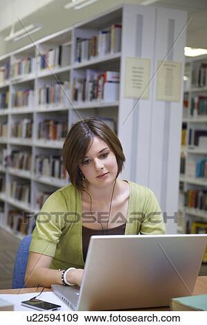 Young woman working on laptop in library View Large Photo Image Stock Photo - Young woman working on laptop in library. Fotosearch