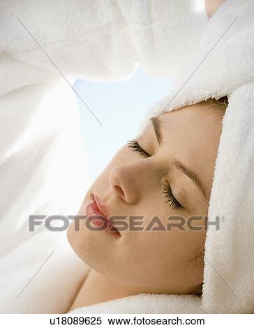 Stock Photography - Caucasian mid-adult woman wearing towel on head with eyes closed relaxing.. Fotosearch