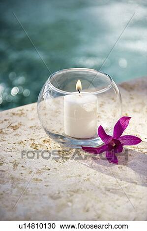Lit candle in glass bowl with purple orchid next to pool View Large Photo Image Stock Image - Lit candle in glass bowl with purple orchid next to pool. Fotosearch