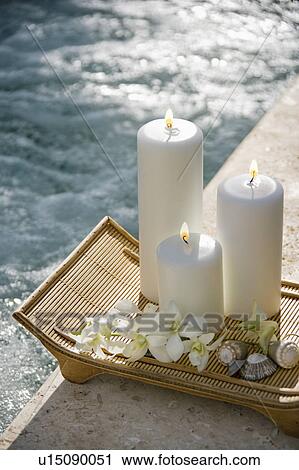 Lit pillar candles on tray with white orchids beside pool View Large Photo Image Stock Image - Lit pillar candles on tray with white orchids beside pool. Fotosearch