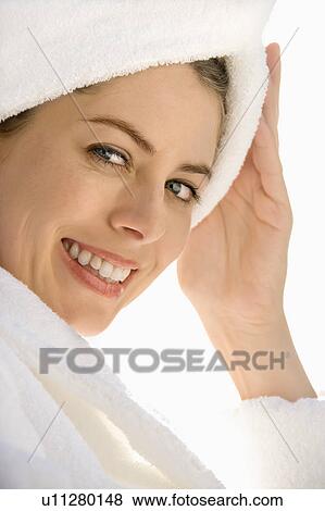 Mid-adult woman wearing towel around head with hand on head smiling at viewer View Large Photo Image Stock Photo - Mid-adult woman wearing towel around head with hand on head smiling at viewer. Fotosearch