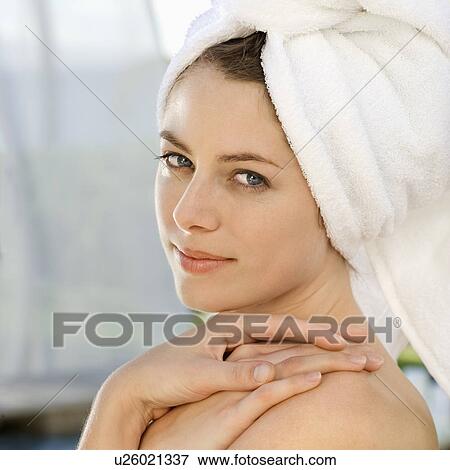 Stock Photo - Mid-adult woman wearing towel around head with hands on shoulder looking at viewer. Fotosearch