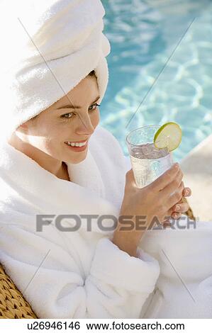 Woman wearing robe and towel on head drinking from glass next to pool View Large Photo Image Stock Photograph - Woman wearing robe and towel on head drinking from glass next to pool. Fotosearch