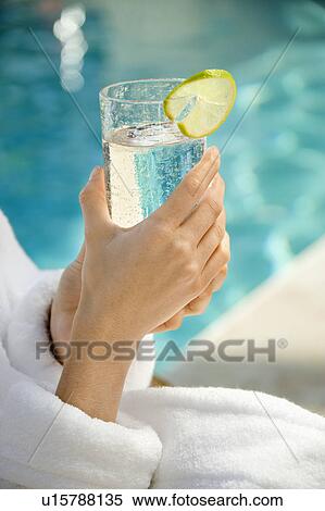 Woman's hands holding beverage glass garnished with lime slice next to pool View Large Photo Image Stock Photography - Woman's hands holding beverage glass garnished with lime slice next to pool. Fotosearch
